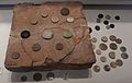 Pottery floor tile incised with lines for use as a game board, with various bone game counters, excavated from Calleva Atrebatum (Silchester). Reading Museum.